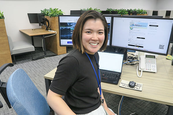 デスクに座ってカメラに微笑む社員の写真
